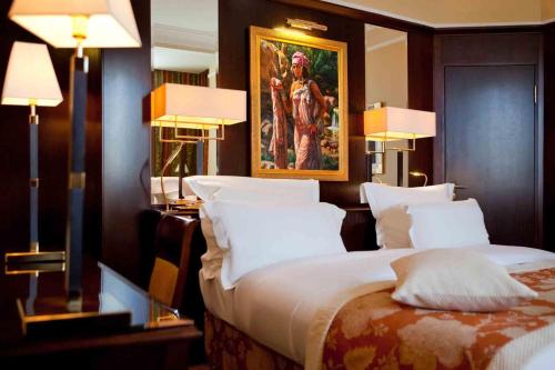a bedroom with a large bed with a painting on the wall at Royal Hotel Oran - MGallery Collection in Oran