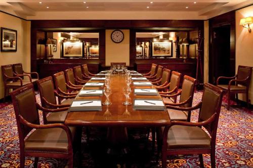 a long table in a room with chairs and a clock at Royal Hotel Oran - MGallery Collection in Oran