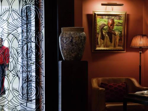 a living room with a vase and a painting on the wall at Royal Hotel Oran - MGallery Collection in Oran
