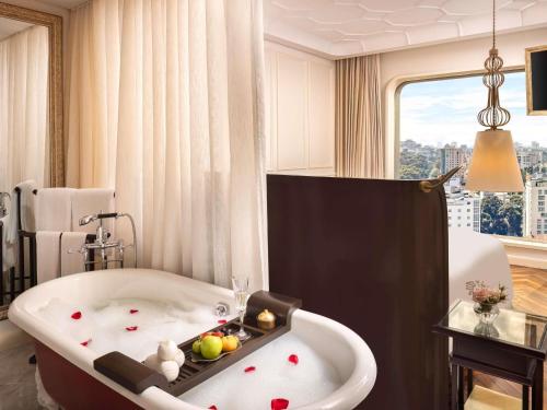 a bath tub in a room with a window at Hotel Des Arts Saigon Mgallery Collection in Ho Chi Minh City