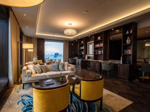 a living room with a couch and a bar at Hotel Des Arts Saigon Mgallery Collection in Ho Chi Minh City