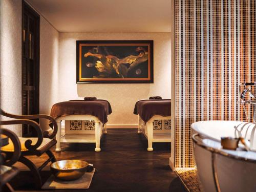 a bathroom with a tub and a painting on the wall at Hotel Des Arts Saigon Mgallery Collection in Ho Chi Minh City