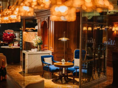 a restaurant with a table and two blue chairs at Hotel Des Arts Saigon Mgallery Collection in Ho Chi Minh City