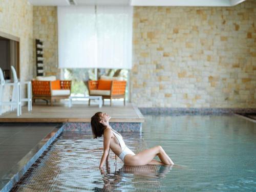 a woman sitting in the water in a swimming pool at Sofitel Tamuda Bay Beach And Spa in M'diq