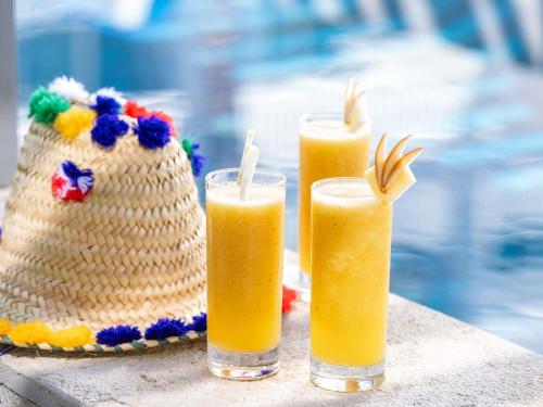 two glasses of orange juice on a table with a straw at Sofitel Tamuda Bay Beach And Spa in M'diq