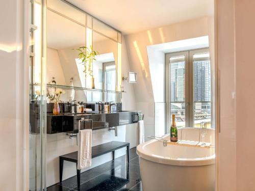 a bathroom with a sink and a tub and a mirror at Sofitel Frankfurt Opera in Frankfurt/Main