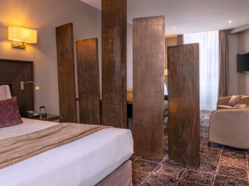 a hotel room with a bed and a desk at La Cour des Consuls Hotel & Spa Toulouse - MGallery Collection in Toulouse