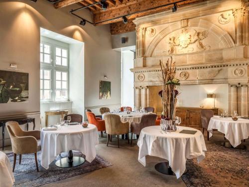 a restaurant with white tables and chairs and a fireplace at La Cour des Consuls Hotel & Spa Toulouse - MGallery Collection in Toulouse
