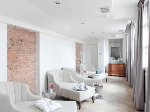 a living room with white furniture and a brick wall at La Cour des Consuls Hotel & Spa Toulouse - MGallery Collection in Toulouse