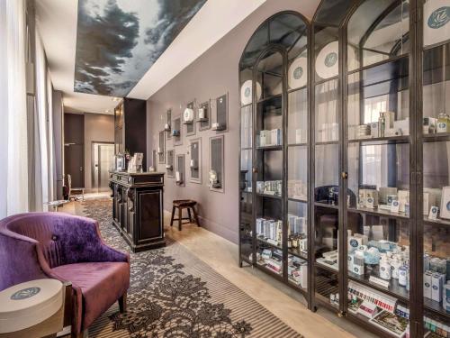 a room with a purple chair and a display case at La Cour des Consuls Hotel & Spa Toulouse - MGallery Collection in Toulouse