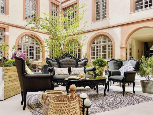 a patio with chairs and a couch and a table at La Cour des Consuls Hotel & Spa Toulouse - MGallery Collection in Toulouse