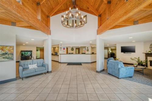 a living room with two blue chairs and a chandelier at SureStay Plus Hotel by Best Western Elizabethtown Hershey in Elizabethtown
