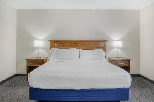 a bed in a hotel room with two lamps on tables at SureStay Plus Hotel by Best Western Elizabethtown Hershey in Elizabethtown