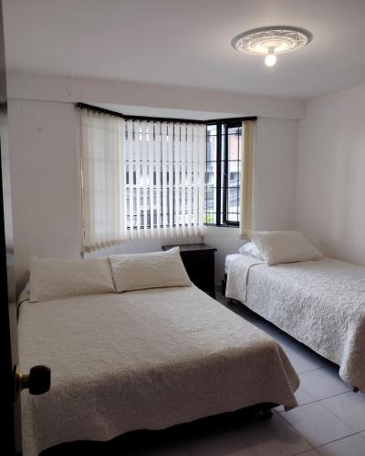 a bedroom with two beds and a window at EL HOSTAL DE FIDELINA in Santa Rosa de Cabal