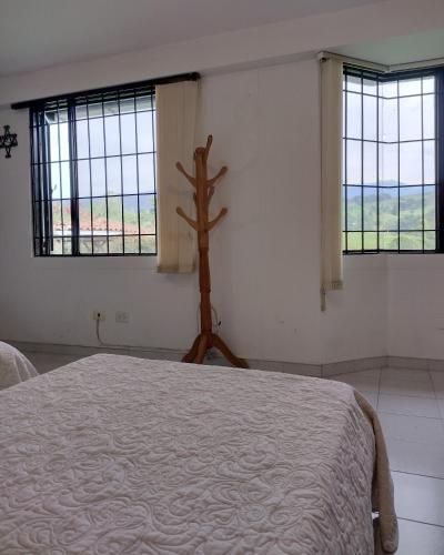 a bedroom with a bed in a room with windows at EL HOSTAL DE FIDELINA in Santa Rosa de Cabal
