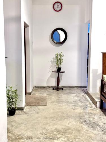 a hallway with a clock on the wall and a table at Coastal Cloud Backpackers Villa in Unawatuna