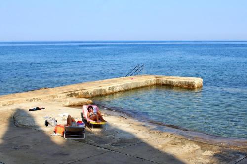 a group of people sitting in chairs in the water at Apartments with parking space Basanija, Umag - 21418 in Bašanija