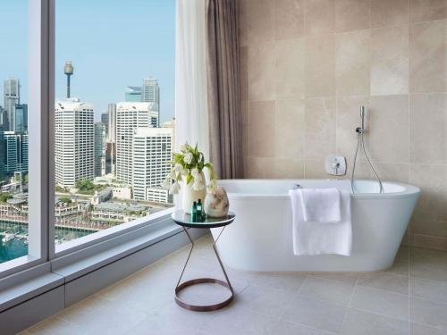 a bathroom with a bath tub and a large window at Sofitel Sydney Darling Harbour in Sydney
