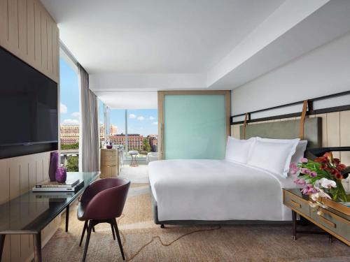 a bedroom with a bed and a desk and a tv at Sofitel Sydney Darling Harbour in Sydney