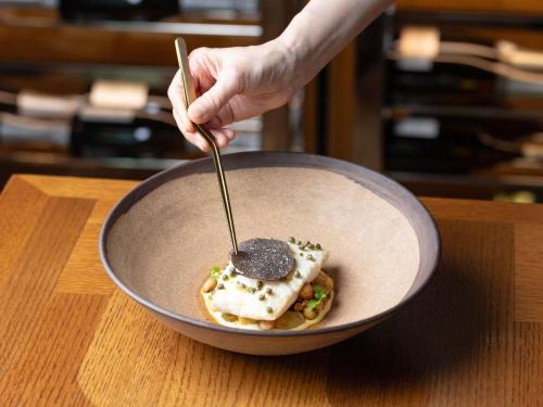 a person holding a spoon in a bowl of food at Sofitel Sydney Darling Harbour in Sydney