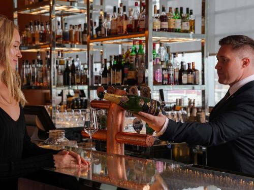 a man pouring a woman a glass of wine at a bar at Sofitel Sydney Darling Harbour in Sydney