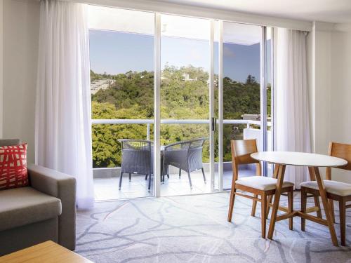 a living room with a table and chairs and a large window at Sofitel Noosa Pacific Resort in Noosa Heads