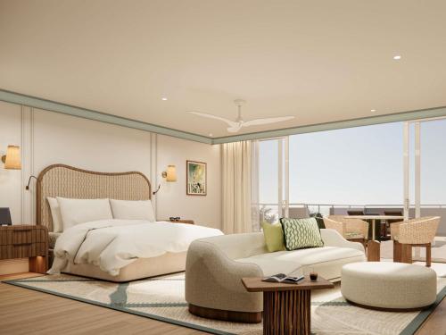 a bedroom with a bed and a couch and a chair at Sofitel Noosa Pacific Resort in Noosa Heads