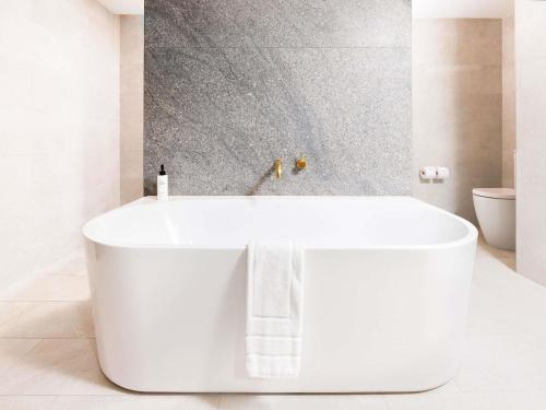 a white bath tub in a white bathroom at Sofitel Noosa Pacific Resort in Noosa Heads