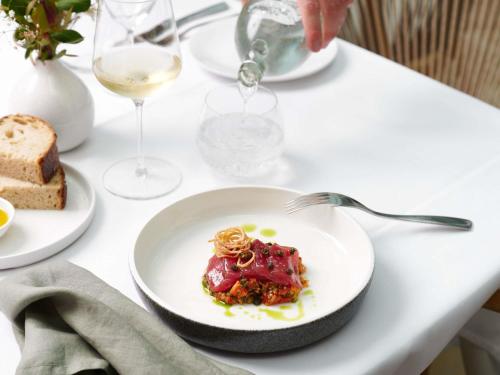 a plate of food on a table with a glass of wine at Sofitel Noosa Pacific Resort in Noosa Heads