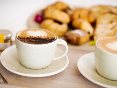 two cups of coffee sitting on a table with pastries at Sofitel Noosa Pacific Resort in Noosa Heads