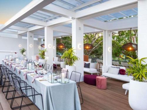 a long table with white tables and chairs in a room at Sofitel Noosa Pacific Resort in Noosa Heads