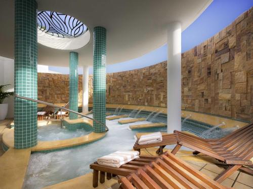 a swimming pool with two benches and a swimming pool at Sofitel Noosa Pacific Resort in Noosa Heads