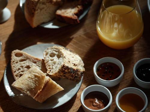 a table with two plates of bread and a glass of orange juice at 5 Terres Hotel & Spa - MGallery Collection in Barr