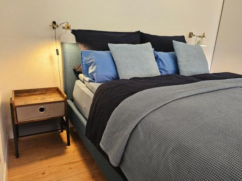 a bedroom with a bed with blue pillows and a table at Ferienwohnung Vogelnest mit weitem Blick über den Schwarzwald in Baiersbronn