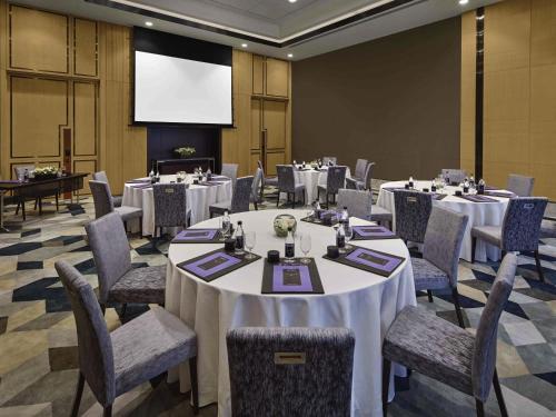 a conference room with tables and chairs and a projection screen at Sofitel Singapore City Centre in Singapore