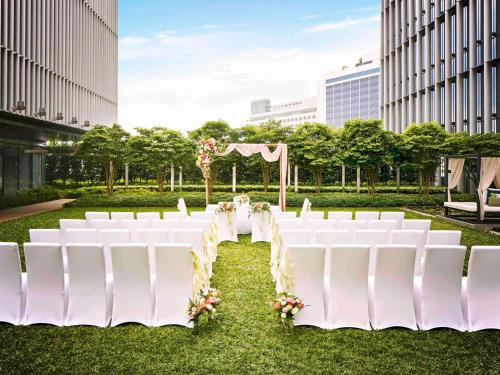 a wedding aisle with white chairs and a marquee at Sofitel Singapore City Centre in Singapore