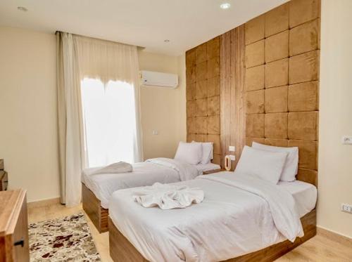 a bedroom with two beds with white sheets and a window at Amon Pyramids View Inn in Cairo