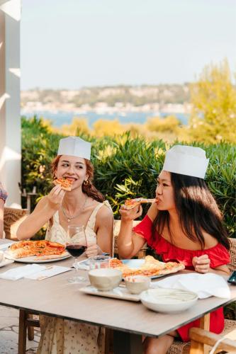 two women are sitting at a table eating pizza at Mangia's Brucoli, Sicily, Autograph Collection in Brucoli