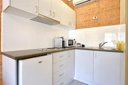 a kitchen with white cabinets and white appliances at Cranbourne Motor Inn in Cranbourne