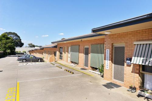 a parking lot in front of a brick building at Cranbourne Motor Inn in Cranbourne