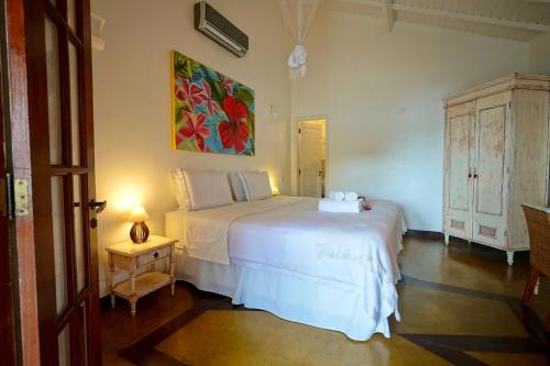 a bedroom with a white bed and a painting on the wall at Casa da Ilha & SPA in Abraão
