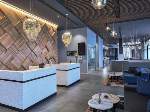 a lobby with a reception area with blue furniture and chandeliers at Tarcin Forest Resort & Spa Sarajevo - MGallery Collection in Tarčin
