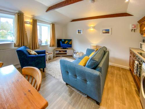 a living room with a blue couch and a table at Wild Rose in Delabole