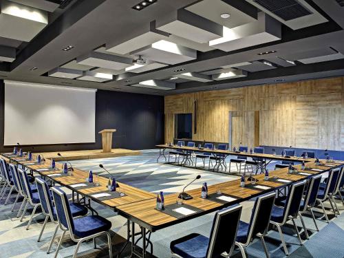 a large conference room with tables and chairs and a podium at Tarcin Forest Resort & Spa Sarajevo - MGallery Collection in Tarčin