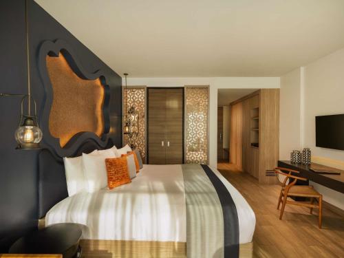 a bedroom with a large bed and a desk at Avista Grande Phuket Karon - MGallery in Karon Beach