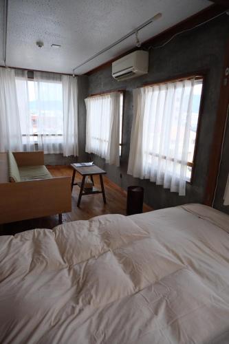 a bedroom with a bed and a table and windows at めくる in Matsumoto