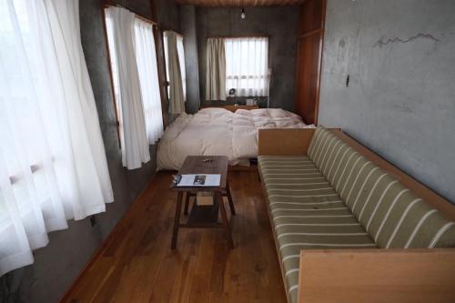 una sala de estar con un sofá y una cama en めくる, en Matsumoto