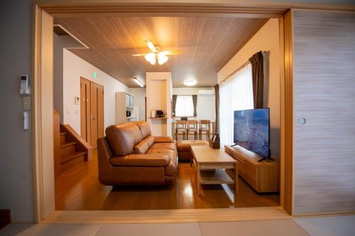 ein Wohnzimmer mit Sofa und Fernseher in der Unterkunft 飛梅の宿Tobiume inn in Dazaifu