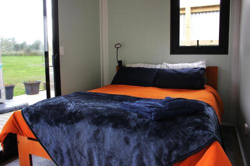 a bedroom with an orange bed with a blue blanket at Night Sky Magic in Olive Grove in Gladstone