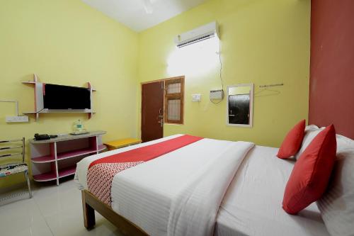 a bedroom with a bed with red pillows and a television at Super Hotel O Vellore New Bus Station Formerly SP Highway Inn in Vellore